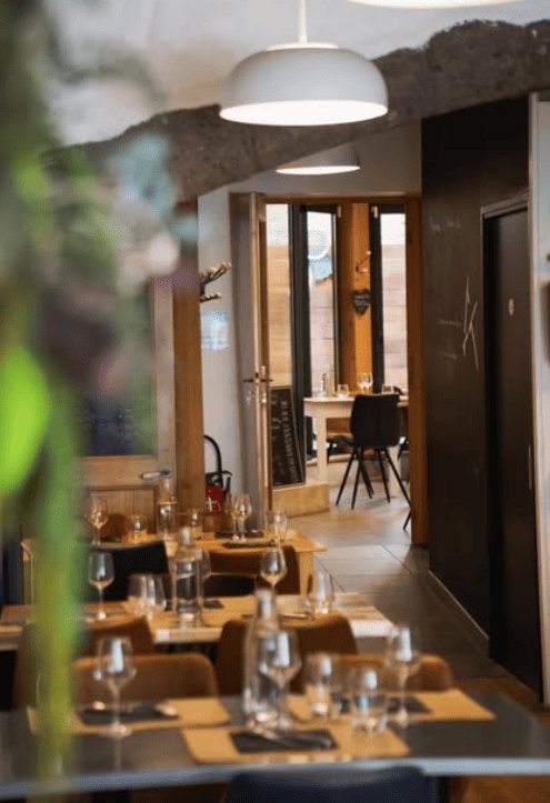 La salle du restaurant, tables dressées sous les poutres
