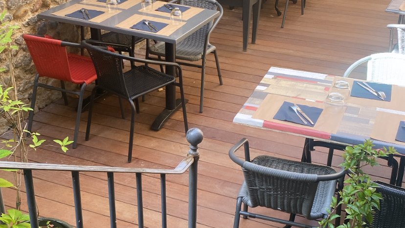 La terrasse en bois du restaurant Lard dans l'assiette, tables dressées dans la cour intérieure à Brioude